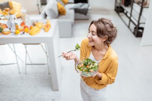 mujer comiendo ensalada con felicidad