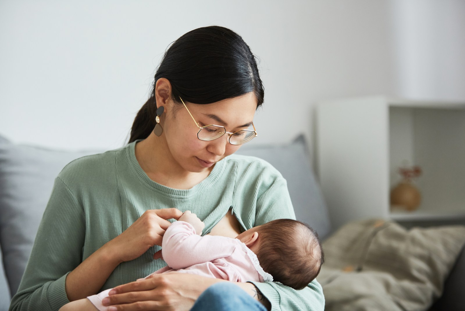 madre asiatica mirando y amamantando a su bebe