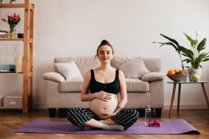 mujer embarazada sentada en el piso feliz tocandose el vientre